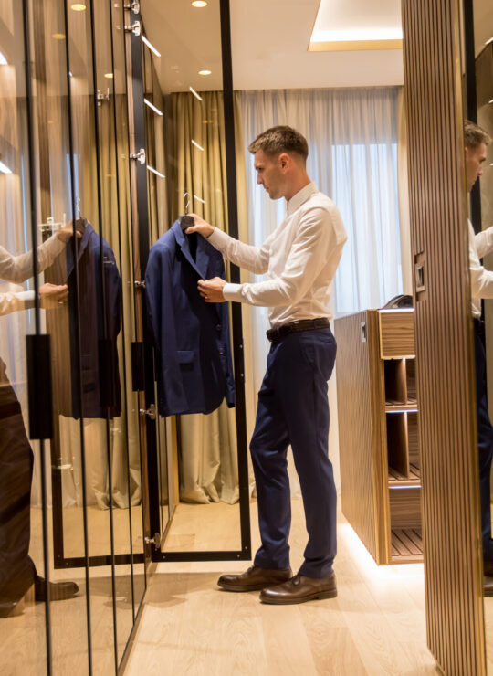 Young man choosing clothes from wardrobe in the hall of contemp - Maydek İnşaat İzmir